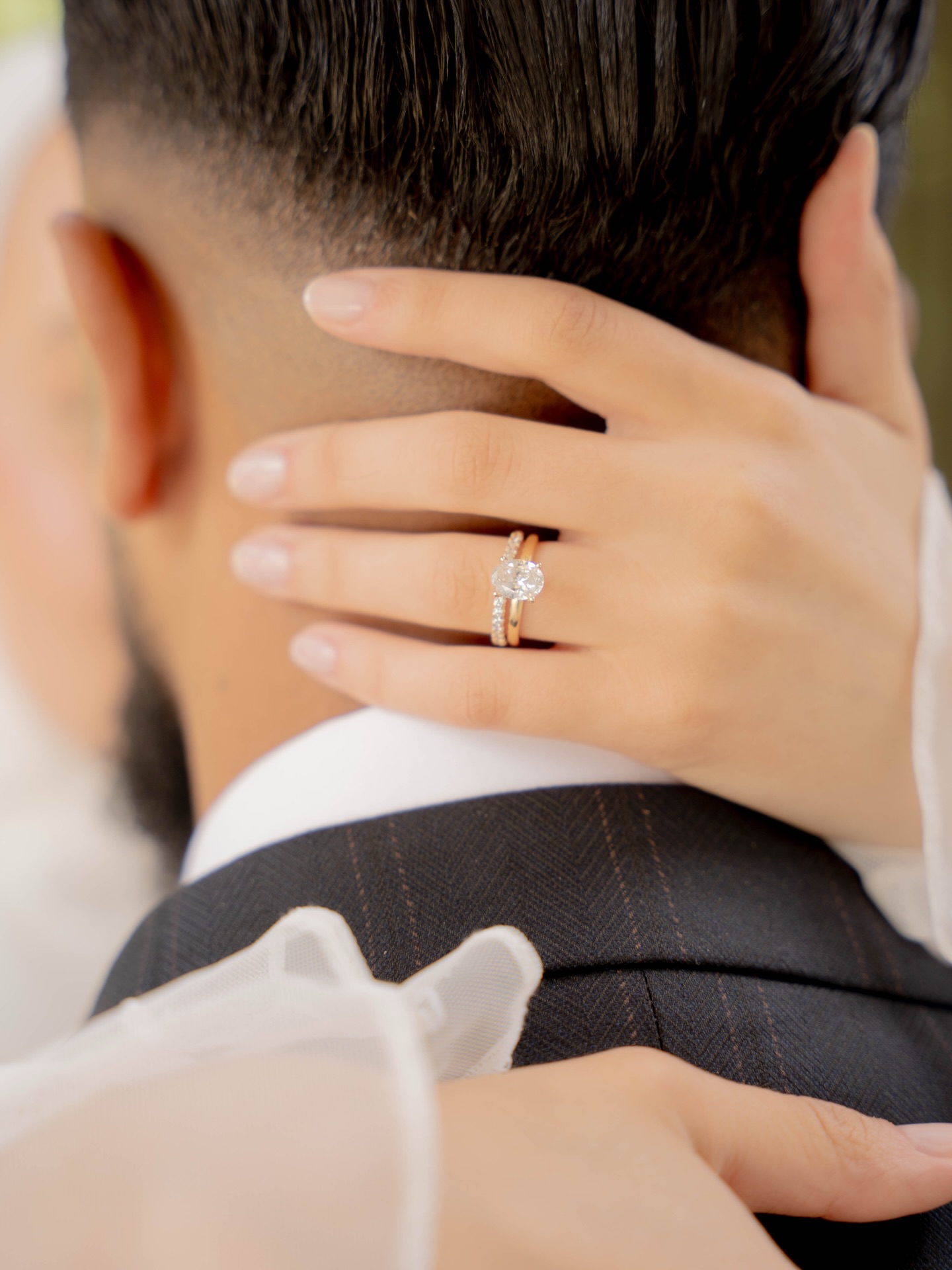 Main de la mariée et bague posées sur l’épaule du marié