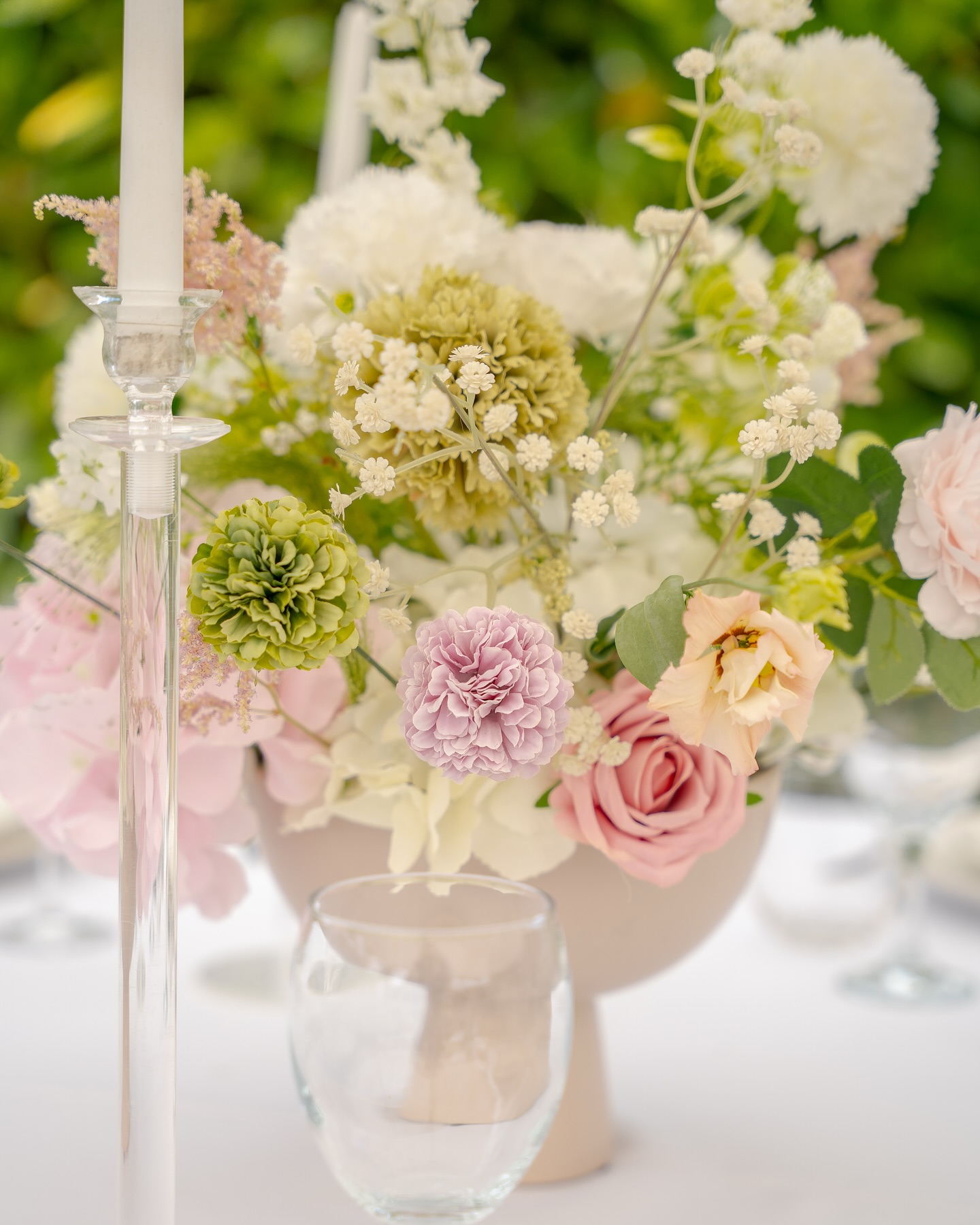 Composition florale pastel et bougie sur une table de mariage