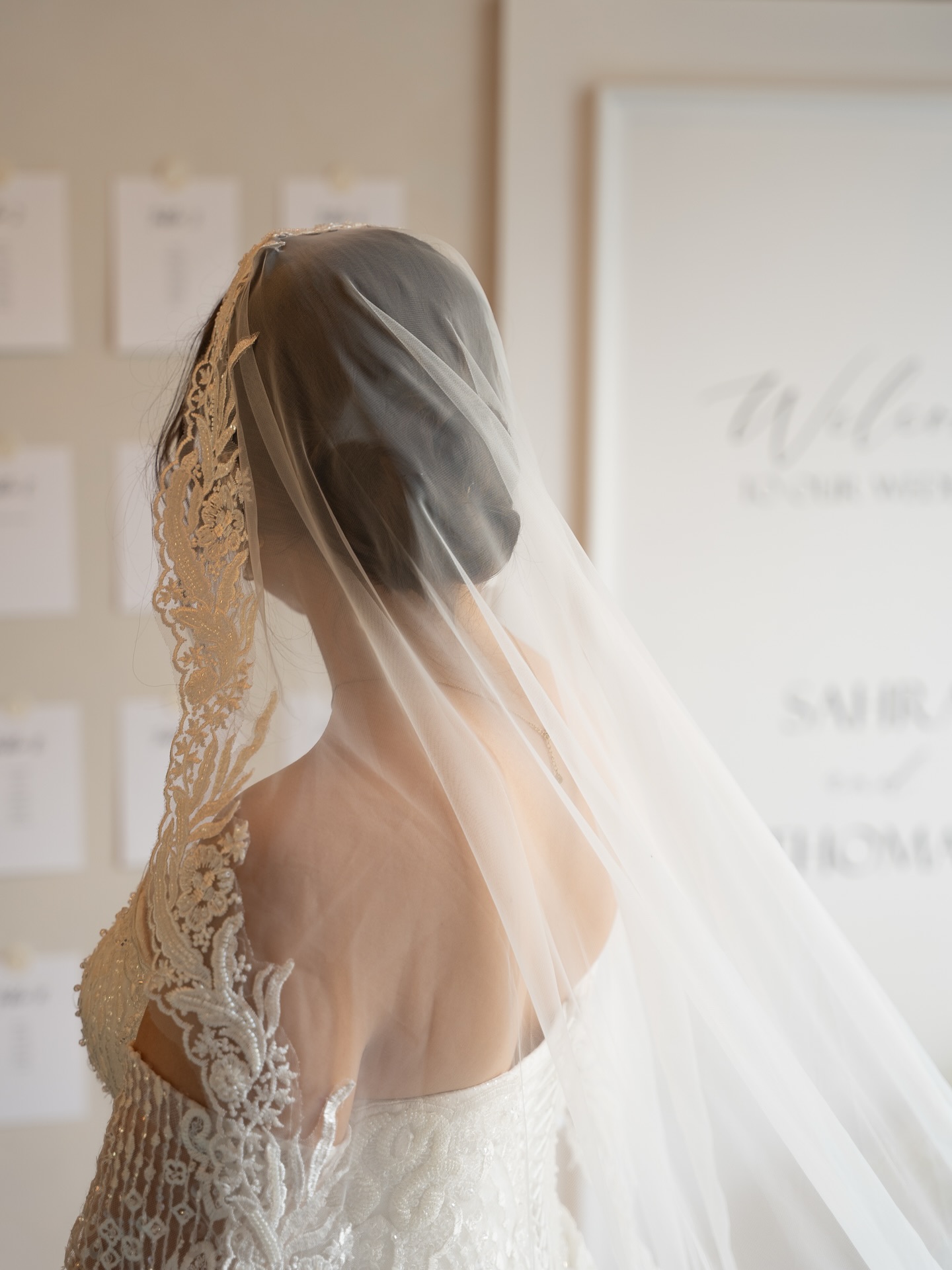 Mariée de dos sous son voile dans une lumière ivoire